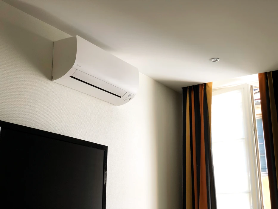 Intérieur d'une chambre d'hôtel avec climatiseur mural **Daikin** de type **split system** monté en hauteur sur cloison blanche