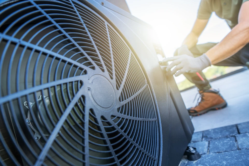 Un technicien effectue l'entretien sur un climatiseur situé sur un toit