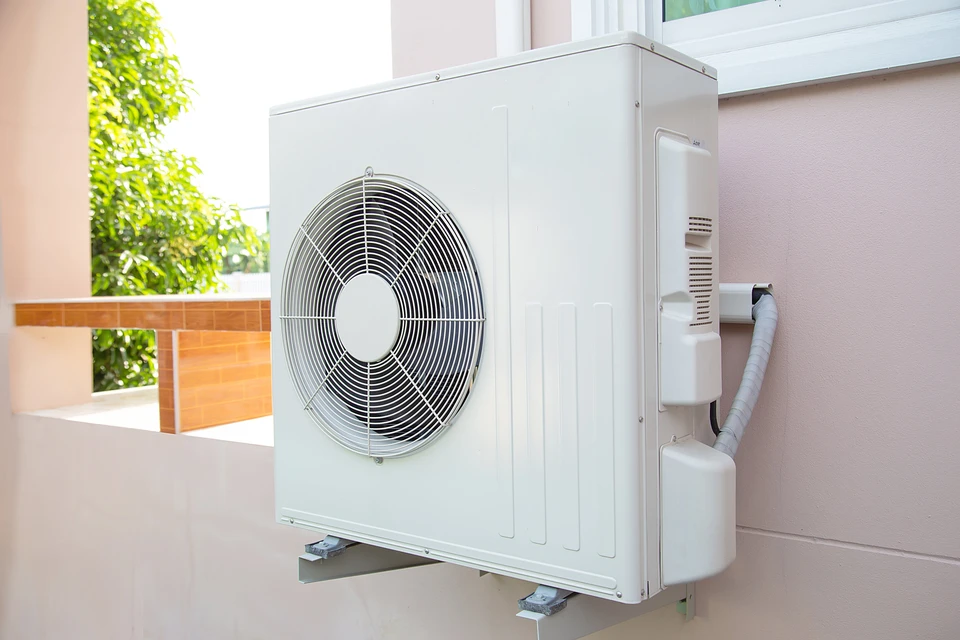 Scène extérieure d'une terrasse résidentielle avec unité de climatisation installée contre un mur rose