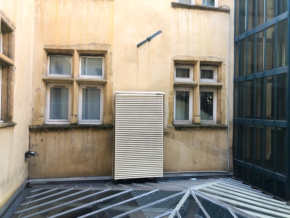 Cour intérieure d'un immeuble haussmannien, façade ocre avec fenêtres à croisillons